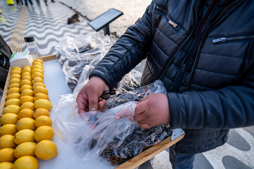 Closeup of fit mature man holding oranges as healthy snack after morning workout at snowy winter forest, panorama. Outdoor sports, balanced diet and cold resistance training concept