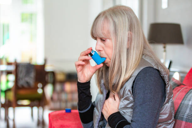 istock Asthmatic senior woman using asthma inhaler at home 2032994416
