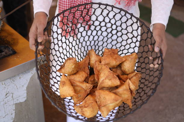 istock image of un recogniged person taking samosa, stuffed with spicy potato,peas, 2033051634