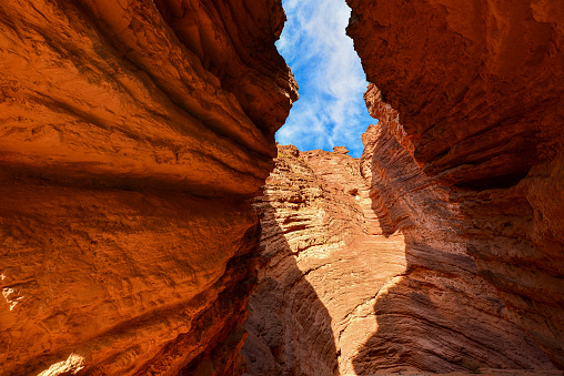 Nestled within the desert of Northern Arizona, Antelope Canyon exhibits the sheer beauty that nature can create. Famous for its lavish colors, unique patterns and complex textures, this slot canyon is a geological wonder that mesmerizes all who venture into its depths.  Carved into the red sandstone of the Navajo Nation, the canyon comes alive with a vibrant spectrum of reds, oranges, and yellows. The sunlight filtering through the narrow openings above casts an ever-changing, warm glow on the smooth, curving walls, creating a surreal play of shifting light and dancing shadows.  The rock formations within the canyon walls bear the unmistakable marks of time and weather. Millennia of wind and water erosion have sculpted the sandstone into flowing, sinuous shapes, creating a sensory experience that is as tactile as it is visual. Touching the canyon's surface connects a person directly to the forces of wind and water that have shaped it over countless millennia.  Antelope Canyon is in Coconino County near Page, Arizona, USA.