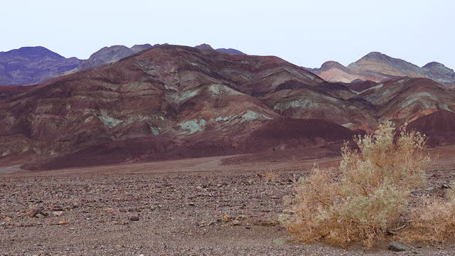 Geological formations of red rocks, Hills in the California desert from various colored clay formations. Desert vegetation around