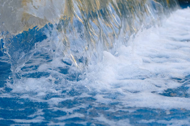 Photo of a stream of water flowing down and hitting the water surface.