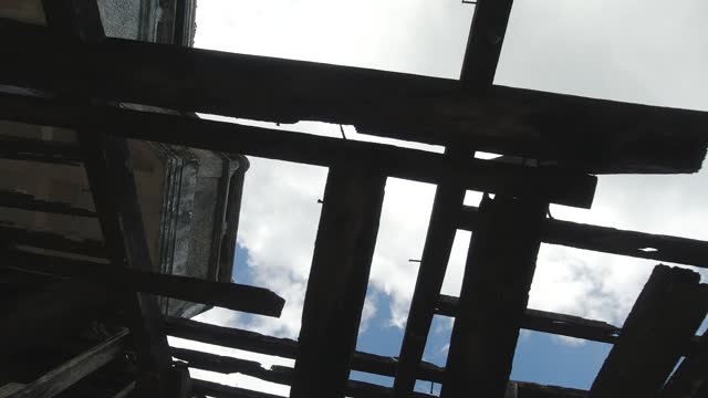 Bottom view of the roof of an old building with wooden structures against the sky. Destroyed wooden roof in the abandoned building. Steadicam shot.