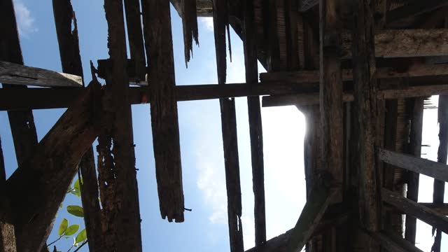 Bottom view of the roof of an old building with wooden structures against the sky. Destroyed wooden roof in the abandoned building. Steadicam shot.