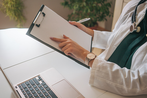 attractive female doctor shows something on the clipboard. He uses a laptop computer. copy space.