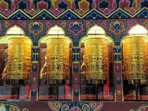 Traditional Tibetan prayer wheels with colorful patterns in the background closeup.