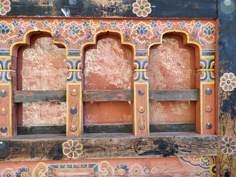 Traditional Bhutanese windows with intricate patterns on a decorated wall, reflecting cultural architecture, Bhutan.