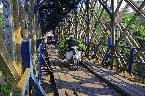 Tasikmalaya, Indonesia, June 16, 2014. Residents cross the Cirahong bridge which connects the Tasikmalaya and Ciamis areas in West Java. This iconic bridge was built in 1893 by the Dutch East Indies government.