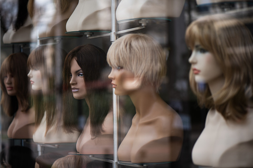 Variety of natural wigs and hairpieces on stand in specialized store