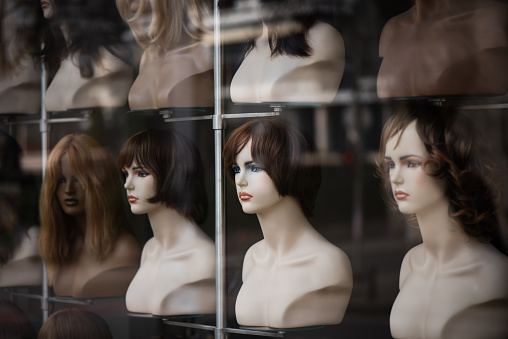 Multi-colored wigs are worn on the heads of mannequins.