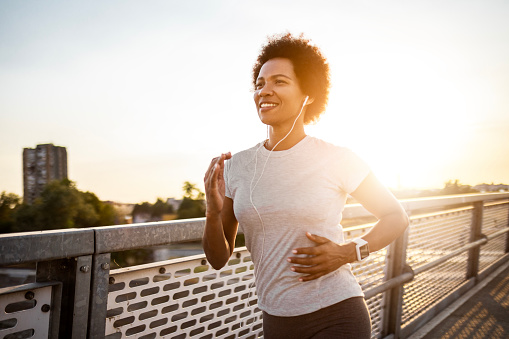 Young African American woman exercising on the bridge at sunset