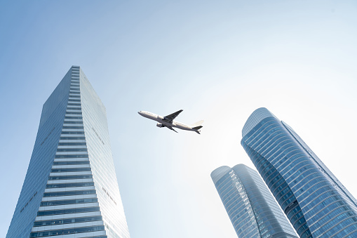 airplane fly over modern office buildings with sky for copy space.