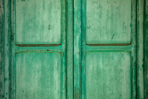Antique double-leaf window aged by time made of natural wood painted in intense light green