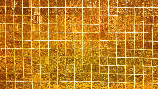 gold yellow square mosaic tiles texture use as background in close up view. grungy glass tiles for decoration for luxury, rich, elegant style concept.