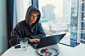 Teenage boy using laptop in a modern city apartment in the evening