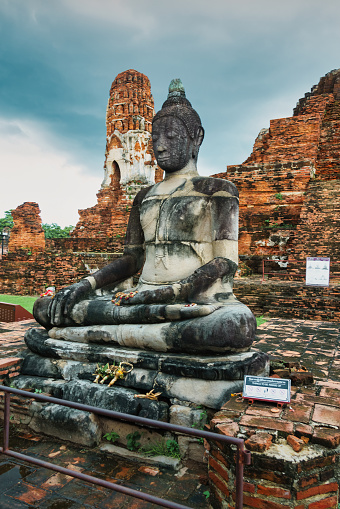Buddha statue at Wat Mahathat in Ayutthaya Historical Park, Ayutthaya, Thailand on a cloudy day, UNESCO World Heritage Site.