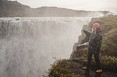 Traveling and exploring Iceland landscapes and travel destinations. Female tourist watching spectacular scenery outdoors. Dettifoss waterfall.