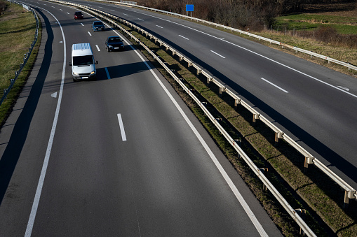 A white minivan and three cars are going down the highway.