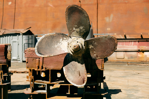 Vintage marine propeller on dry dock background, evoking nautical engineering history and oceanic vessel maintenance.