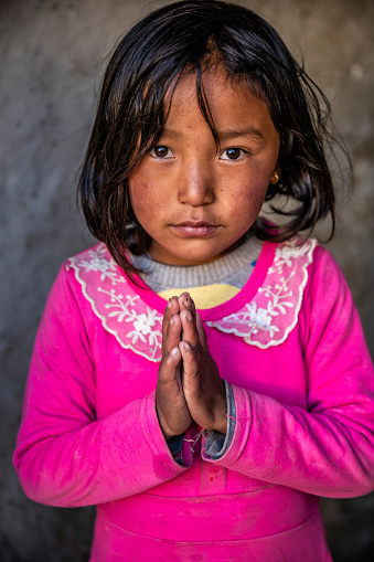 Tibetan girl saying namaste, Lo Manthang, Upper Mustang. Mustang region is the former Kingdom of Lo and now part of Nepal,  in the north-central part of that country, bordering the People's Republic of China on the Tibetan plateau between the Nepalese provinces of Dolpo and Manang.