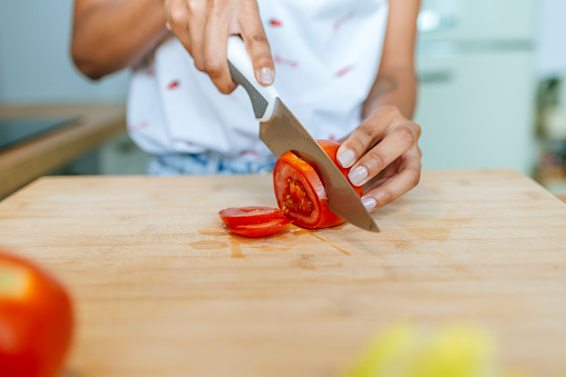Close-up of woman hands cutting tomato.