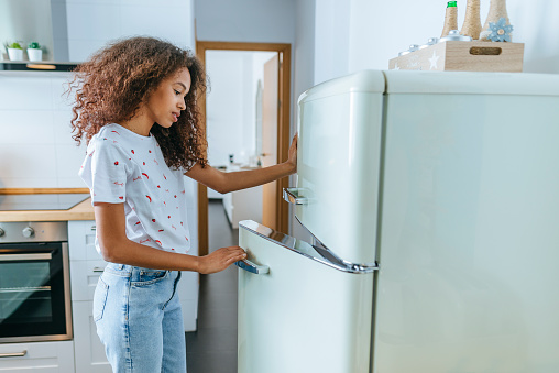 Woman opening the fridge in her home.