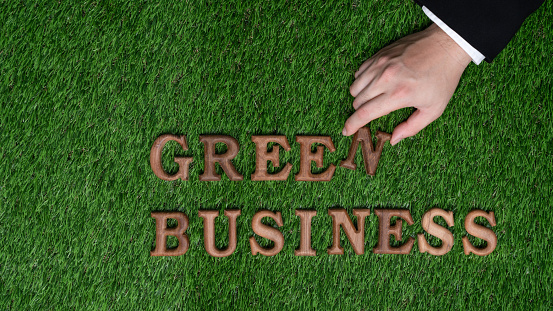 Businessman's hand arrange message in Green Business as concept of corporate effort to commitment to CSR or corporate social responsible concept for environmentally sustainable. Gyre