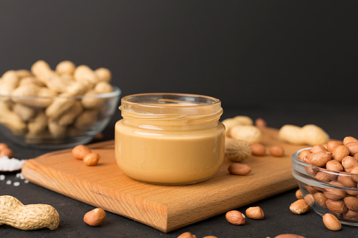 Jar of peanut butter on concrete background, top view