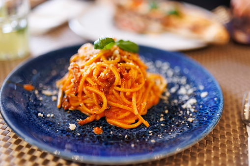 Closeup of spaghetti with nduja, served on a blue plate.\nShot with Canon R5