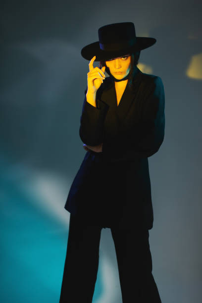 istock Brunette woman in black suit and hat in studio. Retro style 2033483676
