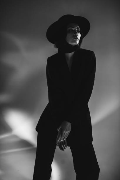 Brunette woman in black suit and hat in studio. Retro style