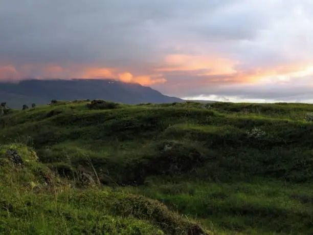 Sunset over green hills in Fossholl, Iceland