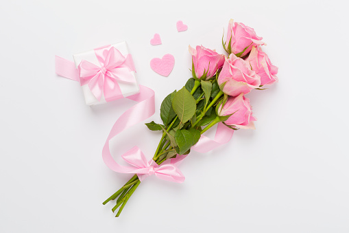 Pink roses with hearts and gift box on color background, top view. Valentines day concept