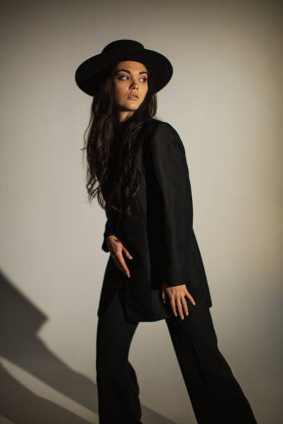 Brunette woman in black suit and hat in studio. Retro style