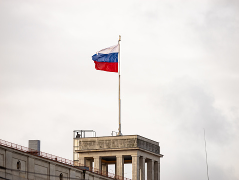 Russian flag on a government building rooftop. Symbol of the country Russia in Europe and sign for an international partnership.