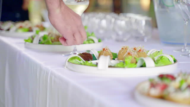 Luxury catering service table for celebration party, arranged buffet table with food trays and drinking goblets, assortment of appetisers, snacks and canape for invited guests, variety of delicious food on beautifully decorated table