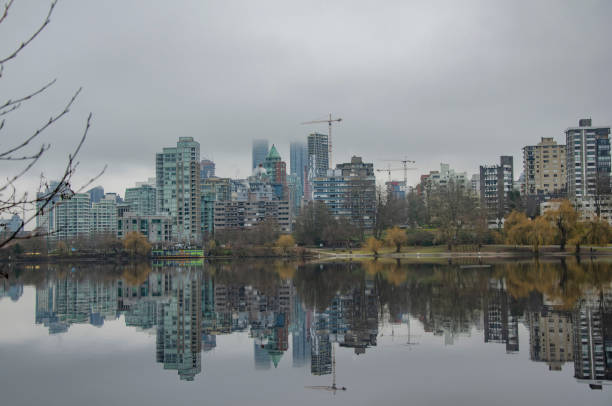 View of downtown Vancouver with buildings reflecting on the water and fog at Lost Lagoon, Vancouver, BC