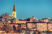 Discover Belgrade's architectural beauty, with churches and towers overlooking the scenic Danube River at night with fullmoon