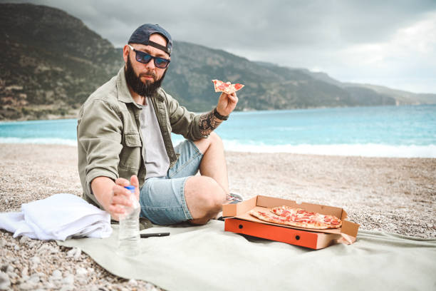 istock Man resting on the beach and eat pizza 2033727271