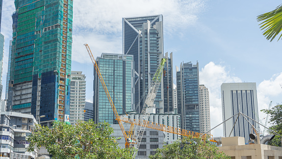 Image of crane and high-rise construction equipment in big city. that are currently constructing new buildings and buildings It is on the left side of the picture during the daytime.