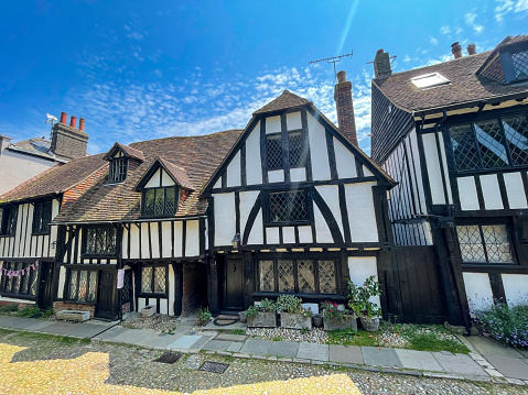 Quaint medieval timbered terraced houses on a charming street in historic town. Walk through a picturesque city of Rye on a sunny summer day. Beautiful tourist attraction in the south of England.