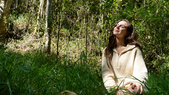 young woman  in the middle of the forest enjoying the sun and nature.