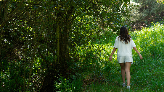 young woman walking in the middle of the forest enjoying the sun and nature.