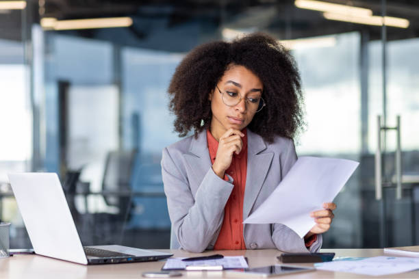 istock Focused businesswoman analyzing document in modern office setting with laptop 2033851427