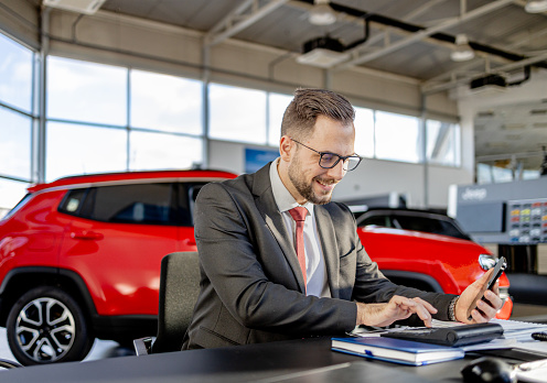 In the car showroom, a man drives deals to their completion with thorough paperwork administration, his expertise paving the road to successful sales