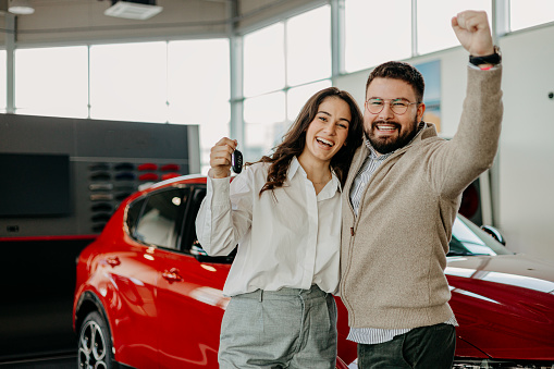 In front of their new car, a couple holds the keys tightly, a symbol of their journey together beginning, filled with hope, excitement, and the freedom of the road ahead