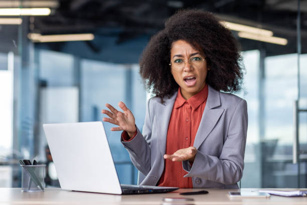 istock Annoyed hispanic businesswoman gesturing with hands in despair while sitting by modern computer at workplace. Irritated female struggling with using portable device and internet connection error 2033909355