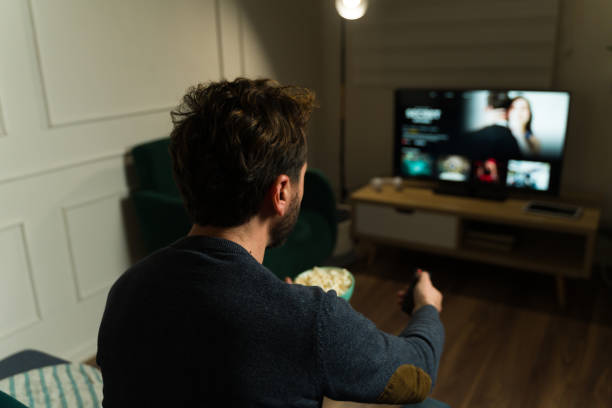 istock Rear view of an hispanic man enjoying watching tv using streaming service 2033911945