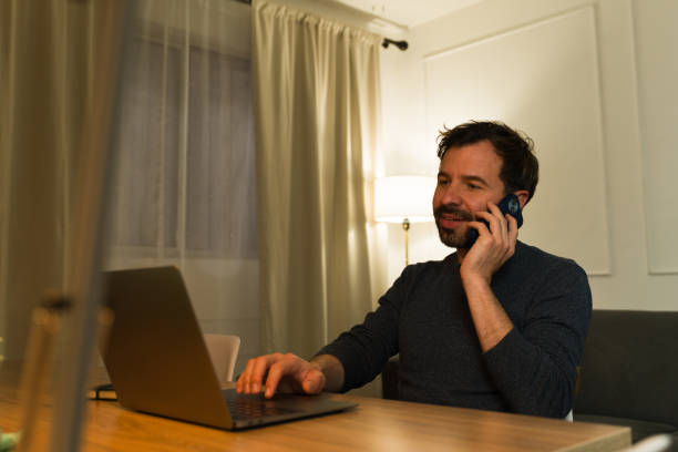 istock Attractive man working from home using the laptop talking on the phone 2033926489