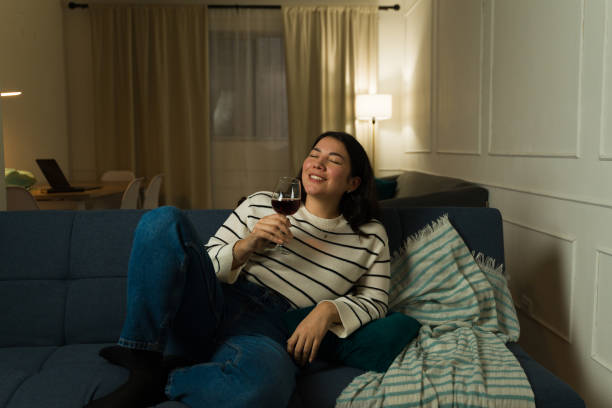 istock Relaxed woman drinking wine sitting on the couch at night 2033932215